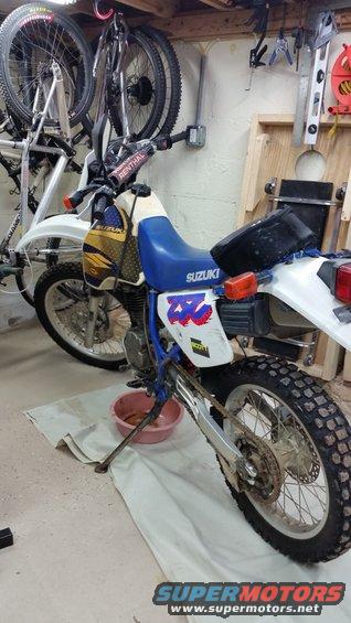 1993 Suzuki DR350S motorcycle, white and blue, with yellow graphics on the tank, parked on a white cloth