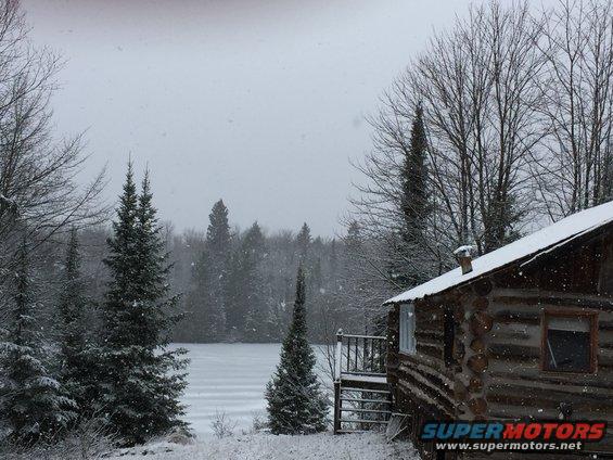 Snowy landscape with log cabin and frozen lake