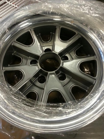 Silver alloy wheel with five spokes and a polished lip, wrapped in plastic