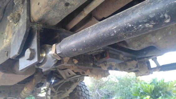 Close-up of a heavy-duty suspension component, possibly a drag link or control arm, attached to a vehicle's frame