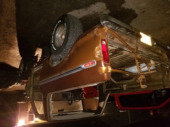 Brown SUV on its side, showing the interior and spare tire mounted on the rear. The vehicle appears damaged