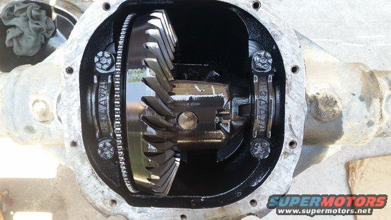 Open differential housing with gears visible. Some text is stamped on the housing