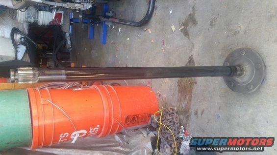 Axle shaft with splined end and flange, resting on orange and green buckets