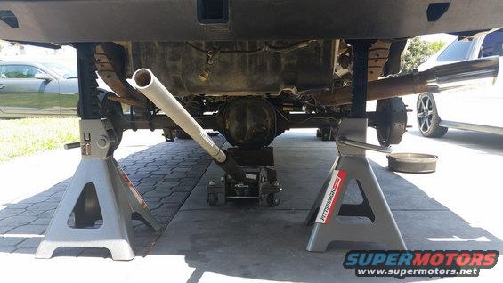 1992 Ford Bronco rear axle supported by jack stands, with a floor jack underneath