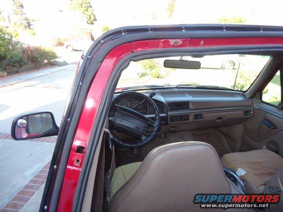 Red SUV interior with tan seats and dashboard, viewed from the passenger side door opening