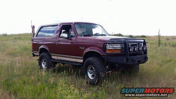 1996 Ford Bronco with aftermarket bull bar and lights parked in a grassy field