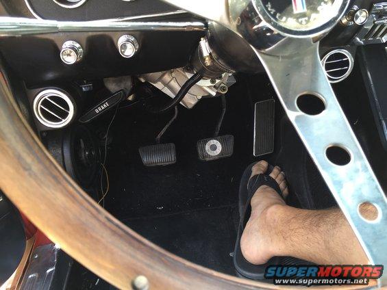 1965 Ford Mustang interior showing brake pedal, clutch pedal, accelerator pedal, and steering wheel