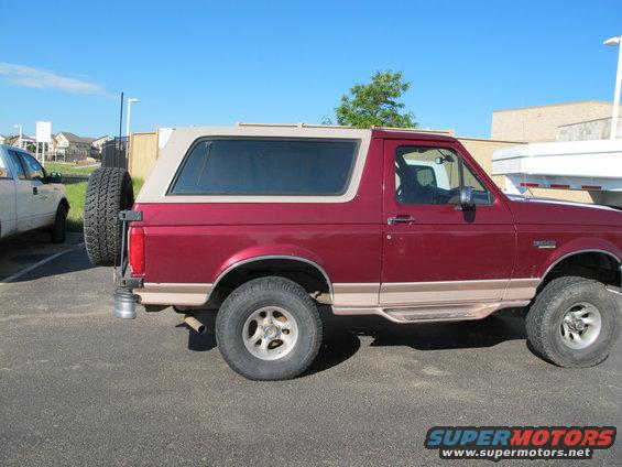 Red 1996 Ford Bronco side view with tan top and rear spare tire