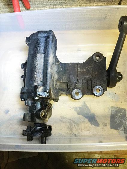 Power steering gearbox with linkage arm, sitting in a plastic bin