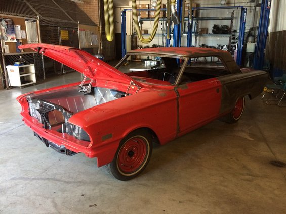 1964 Ford Fairlane coupe in garage, hood open, undergoing restoration
