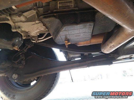 Underside view of vehicle transmission pan with drain plug and exhaust pipe