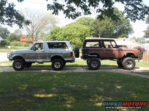 Silver Ford Bronco parked next to a rusty Ford Bronco, both lifted