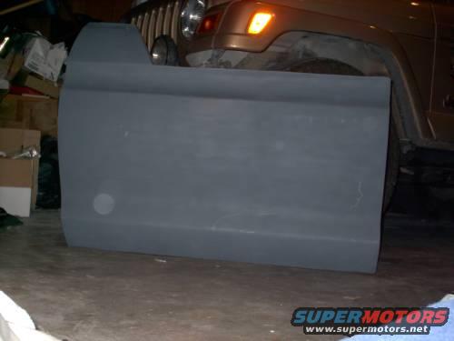 Gray vehicle door in garage, part of a Jeep visible in background