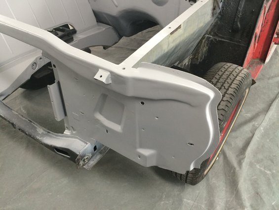 Car frame with gray primer and a tire with red stripe