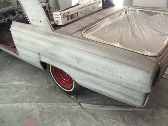 1964 Ford Fairlane rear quarter panel and trunk area in primer, red wheel with whitewall tire visible