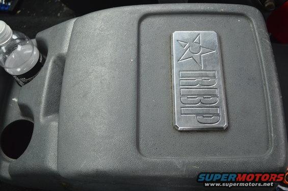 Gray center console with a metal RBP badge and a water bottle in a cup holder
