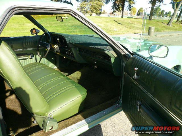 Interior of a green classic car, showing the seat, dashboard, and door panel