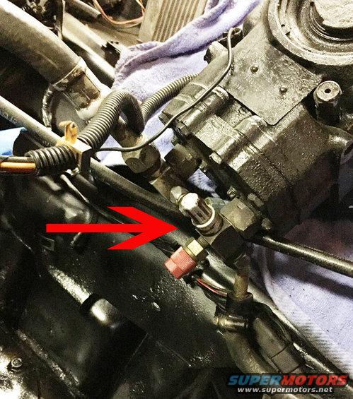 close-up of power steering pump with red arrow pointing to a fitting