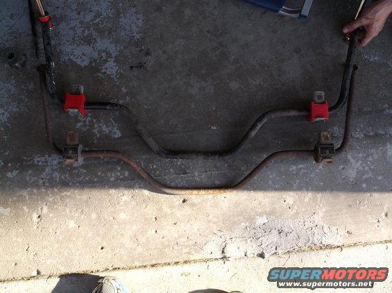 Two metal sway bars with red and black bushings on concrete