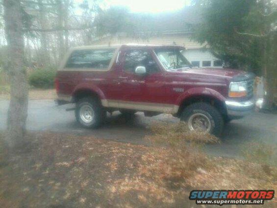 Red 1992 Ford Bronco SUV parked on a gravel driveway, side view