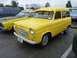 1969 Lincoln Continental - A yellow van is parked next to another yellow vehicle, with a blue SUV in the background.