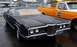 1969 Lincoln Continental - A dark sedan, possibly a 1970 Ford LTD, is parked outside with a sign on its windshield indicating it is for sale.