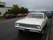 1969 Lincoln Continental - A white sedan with a distinctive chrome grille and license plate FR 3134 is parked on a wet road, with other vehicles visible in the backgr…