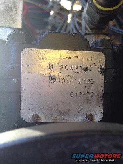 Metal plate with numbers M 2069141, R210L-16753, and 012-72, attached with two screws