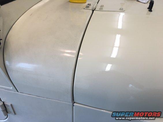 Cream-colored Jeep hood and fender seam with visible panel gaps and bolts