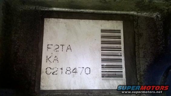 Label with text F2TA, KA, C218470 and a barcode on a dark metal surface