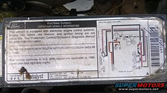 Vehicle information sticker with vacuum hose routing diagram and text about emissions