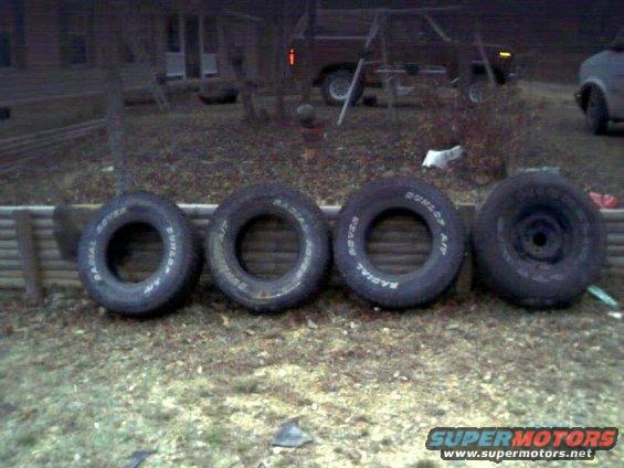 Four tires lined up on the ground. Three have text: RADIAL ROVER and DUNLOP A/T