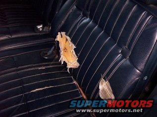 Dark blue vinyl car seat with large tear exposing stuffing