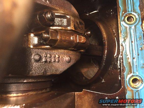 Close-up of engine crankshaft bearings and connecting rod bolts. Some numbers are visible on the engine block