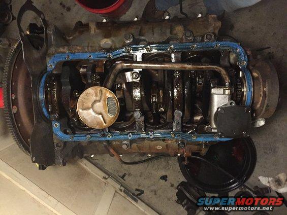 Engine with oil pan removed, showing crankshaft and oil pickup screen. Supermotors.net logo visible