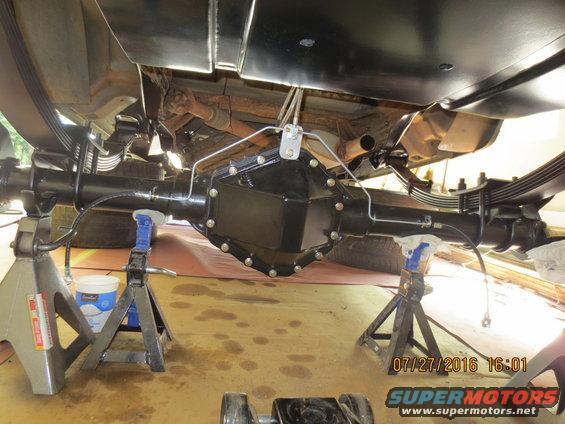 rear axle assembly on jack stands, with leaf springs and brake lines visible