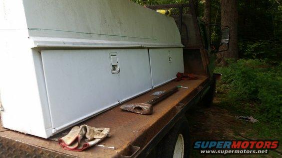 Truck bed with white toolboxes and an axe on a rusty surface