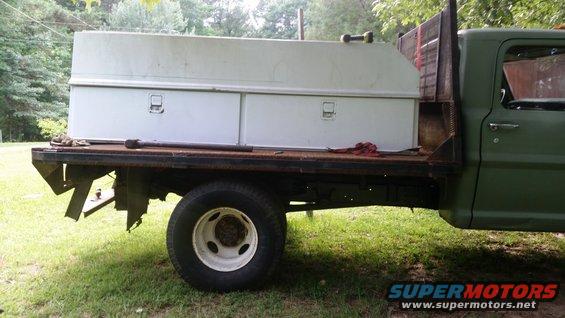 Green flatbed truck side view, showing toolboxes mounted on the bed