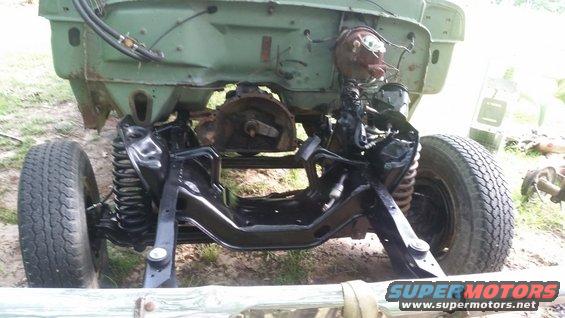 Front chassis and suspension of a vehicle undergoing restoration. The green body is visible above the frame