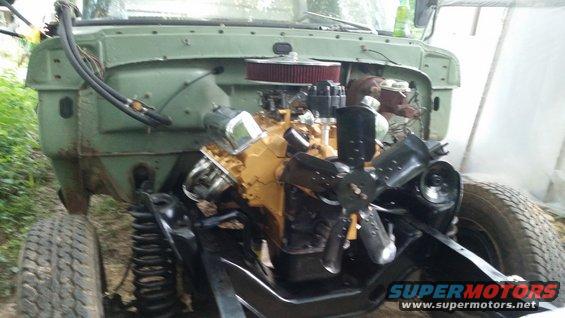 Front end of a green truck with engine exposed, showing V8 engine, air filter, and fan