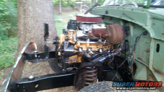 Engine bay of a green truck, showing the V8 engine, brake booster, and part of the frame