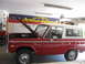 1964 Ford Galaxie - A red Ford Bronco sits in a garage with its hood open, displaying a 'California Action Heroes' banner in the background.