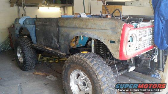 1979 Ford Bronco under repair, showing rusted body panels and large off-road tires
