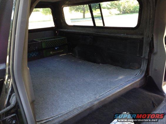 Interior view of a pickup truck bed with carpet and two milk crates