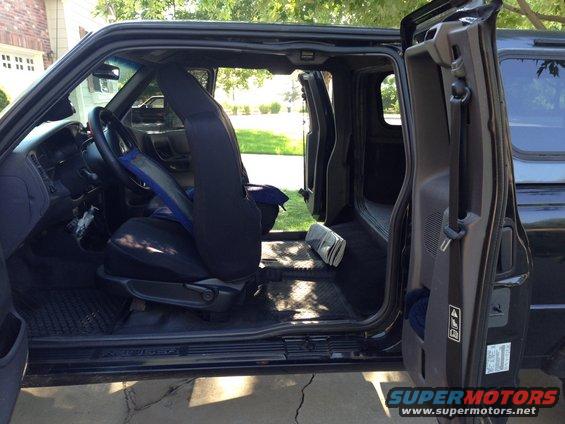 Interior view of a pickup truck with front doors open, showing seats and floor mats