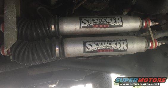 Underside view of two silver Skyjacker 9000 suspension shocks with black bellows