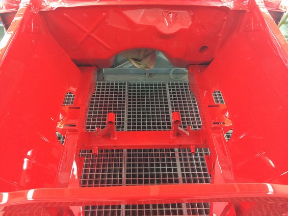 Red painted car chassis interior with a metal grate floor
