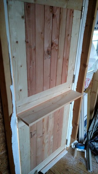 Unfinished wooden door with a shelf installed