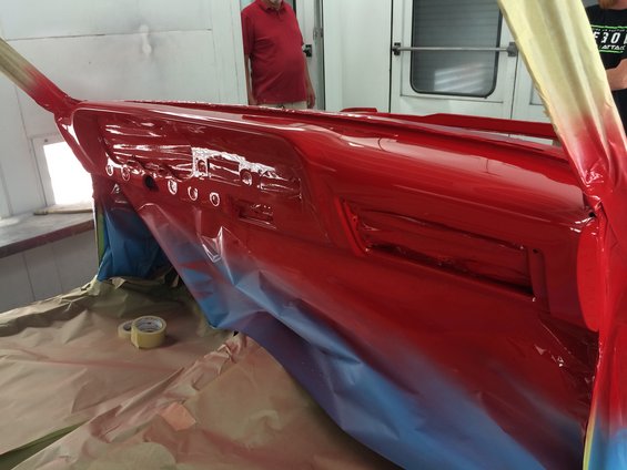 red painted dashboard with circular gauges, being prepped for paint in a booth