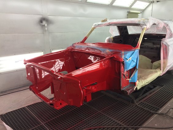 Red 1964 Ford Fairlane body in paint booth, front quarter view